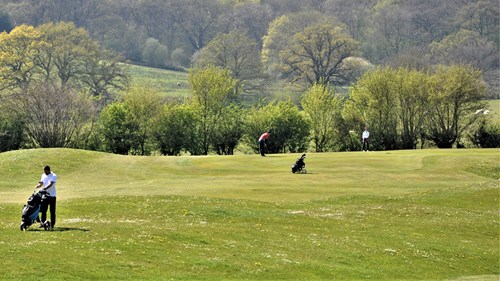 Two players on 14th green looking across from the 17th Fairway